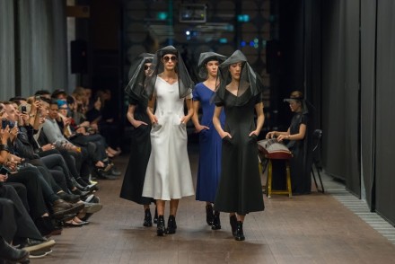 Four models walking down the catwalk at the Lui Hon runway show in Melbourne in different coloured dresses.