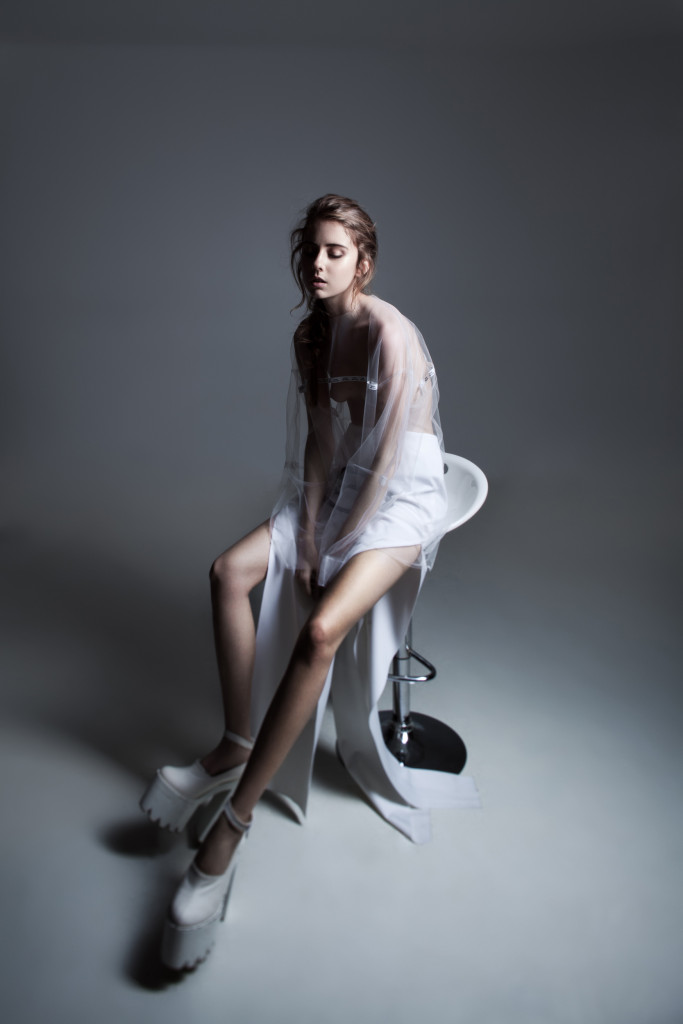 Girl sitting on a stool in a studio being photographed for a modelling shoot.