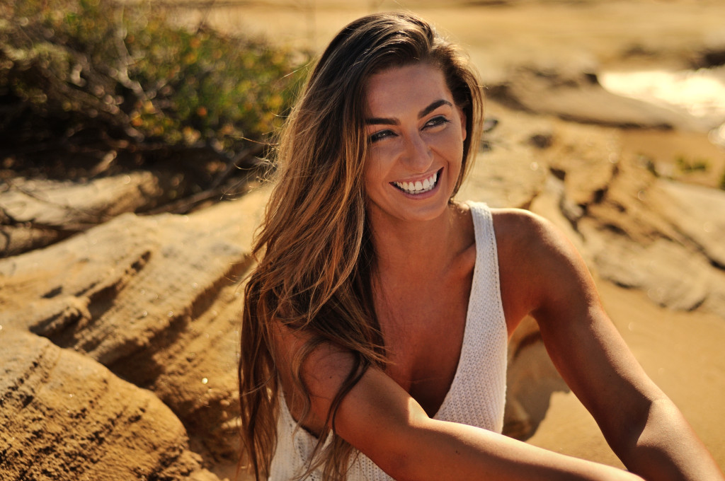 Rebecca Colalillo modelling on seaside rocks for her new tanning product GlowbyBeca.