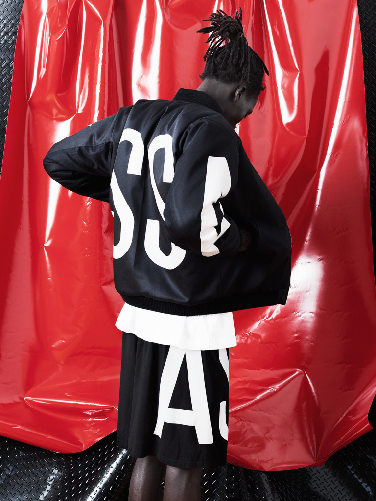 Autumn/Winter 2015 - Male model dressed in ASSK - black and white bomber jacket with matching pants standing in front of a red vinyl sheet. Street wear at it's best.