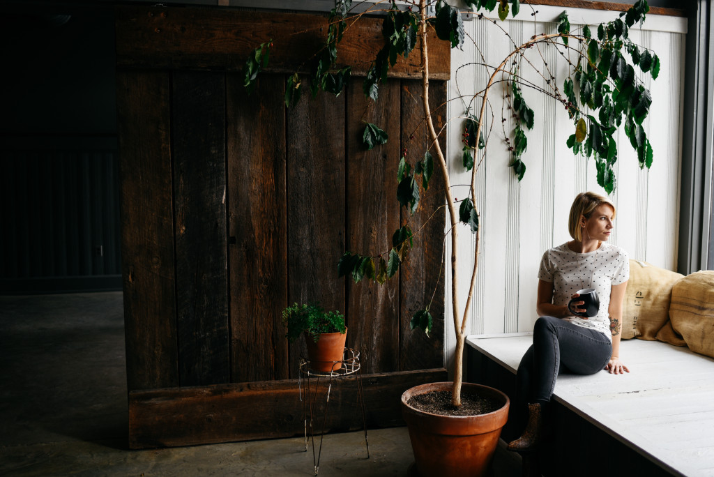 Michelle Houghton sitting in a window box drinking coffee.