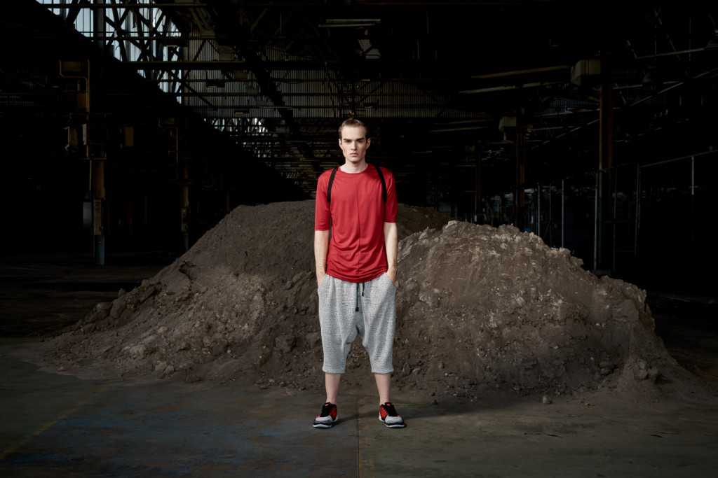 Model standing in an urban setting under a bridge dressed in the sports-luxe wear and technical fabric inspired by pop and internet culture, and elemental street styling.