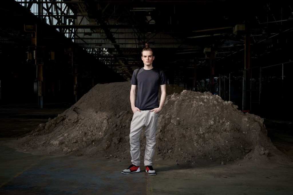 Model standing in an urban setting under a bridge dressed in the sports-luxe wear and technical fabric inspired by pop and internet culture, and elemental street styling.