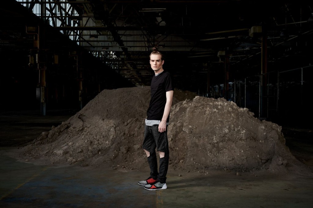 Model standing in an urban setting under a bridge dressed in the sports-luxe wear and technical fabric inspired by pop and internet culture, and elemental street styling.