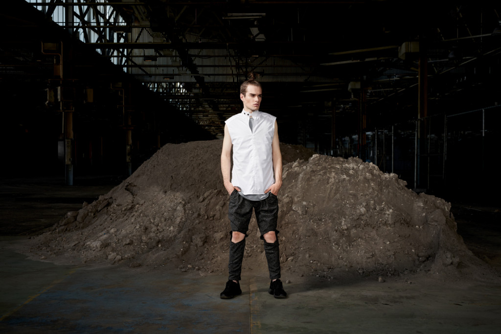 Model standing in a area of earth moving soil in casual sports luxe attire.