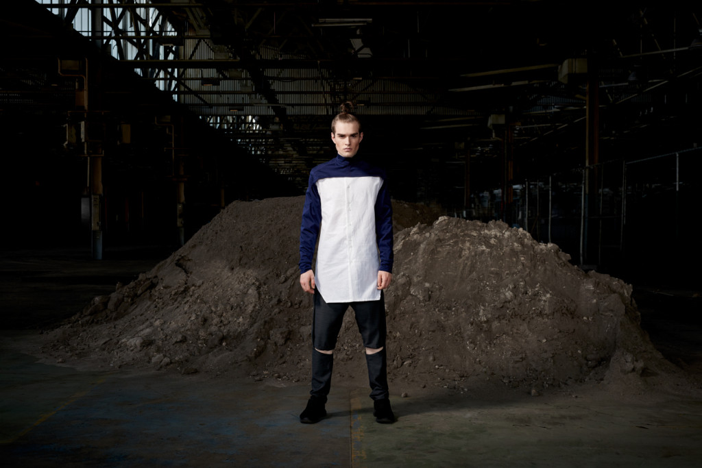 Model standing in an urban setting under a bridge dressed in the sports-luxe wear and technical fabric inspired by pop and internet culture, and elemental street styling.