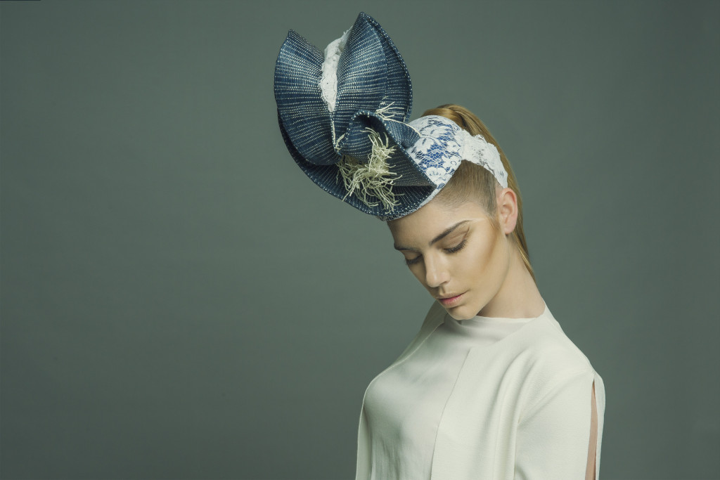 Model standing in a studio wearing the millinery work of Andrew Cannon, a Canberra milliner know as Andrew James Millinery. 