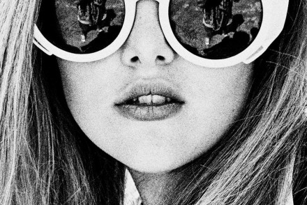 Picture of a girl in black and white with large round sunglasses and long brown hair.