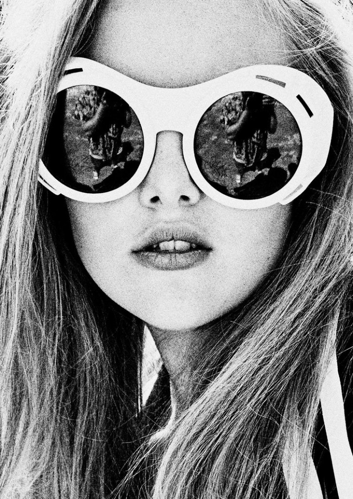 Picture of a girl in black and white with large round sunglasses and long brown hair.